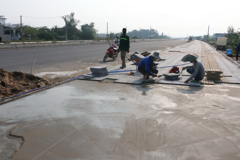 Công nhân đang hoàn thiện vỉa hè tuyến đường Tỉnh lộ 823D (trục mở mới Tây Bắc kết nối Long An- Thành phố Hồ Chí Minh). (Ảnh: Thanh Bình/TTXVN)