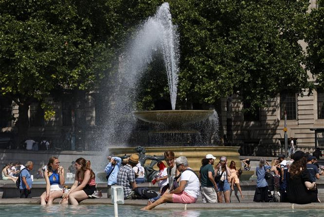Người dân làm mát tại đài phun nước do nắng nóng gay gắt ở London, Anh ngày 17/6/2022. Theo Văn phòng khí tượng Anh, 50% khả năng nhiệt độ nước này trong ngày 18 và 19/7 sẽ lần đầu tiên vượt 40 độ C. (Ảnh: AFP/TTXVN) Châu Âu đứng trước tuần nắng nóng khắc nghiệt như đổ lửa ảnh 1