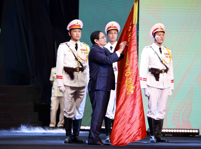 Thủ tướng Phạm Minh Chính gắn Huân chương Hồ Chí Minh lên lá cờ truyền thống của lực lượng Cảnh sát Nhân dân, Bộ Công an. (Ảnh: Phạm Kiên/TTXVN) Lực lượng Cảnh sát nhân dân: Viết tiếp bản anh hùng ca chiến thắng ảnh 1