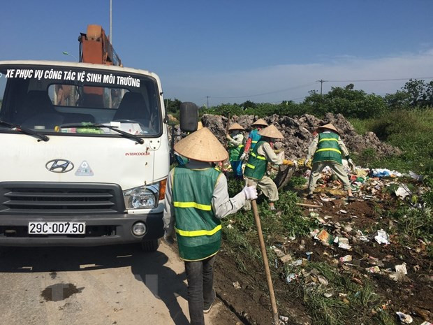Công nhân Công ty Một thành viên Môi trường đô thị Hà Nội thu dọn rác thải bị đổ trộm tại Đại lộ Thăng Long. (Ảnh: Mạnh Khánh/TTXVN) Hà Nội: Cần sớm ngăn chặn nạn đổ trộm phế thải ra đường ảnh 1