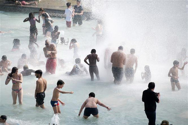 Người dân tránh nắng nóng bên vòi phun nước ở Paris, Pháp, ngày 26/6/2019. (Nguồn: THX/TTXVN) Pháp có nhiệt độ kỷ lục, 1 người Tây Ban Nha tử vong vì nắng nóng ảnh 1