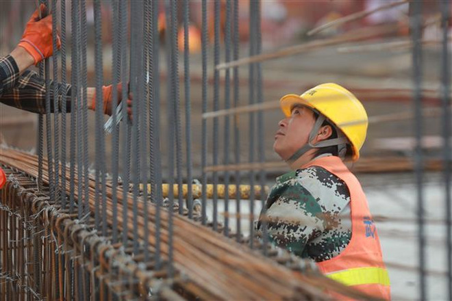 Công nhân làm việc tại một công trường xây dựng ở tỉnh Quý Châu, Trung Quốc. (Nguồn: THX/TTXVN) Cuộc chiến thương mại giữa Mỹ và Trung Quốc: Chuyện đường dài ảnh 1