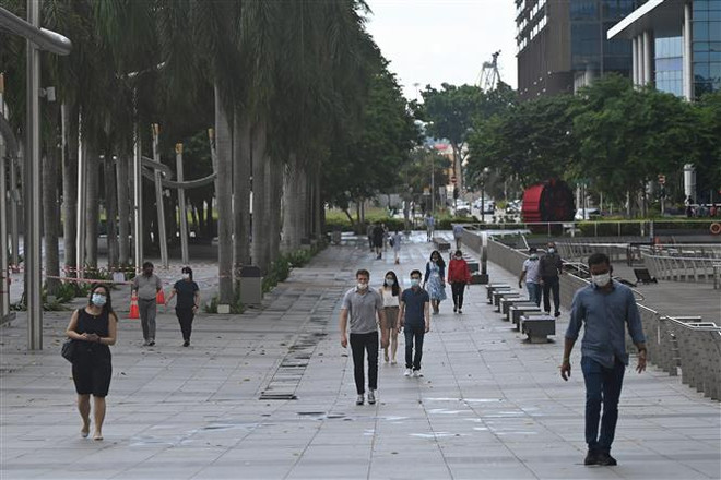 Người dân đeo khẩu trang và giữ khoảng cách phòng dịch COVID-19 tại Vịnh Marina, Singapore ngày 14/5/2021. (Nguồn: AFP/TTXVN) COVID-19 ở Đông Nam Á: Singapore có số ca mắc cao nhất kể từ tháng 1 ảnh 1