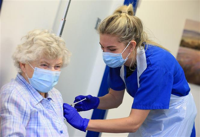 Một cụ bà được tiêm vaccine ngừa COVID-19. (Nguồn: AFP/TTXVN) Scotland triển khai 'hộ chiếu vaccine,' kêu gọi người dân thận trọng ảnh 1