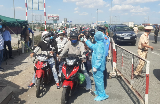 Nhân viên y tế đo thân nhiệt người ra vào Thành phố Hồ Chí Minh tại chốt kiểm dịch. (Ảnh: Đinh Hằng/TTXVN) TP Hồ Chí Minh xác định 3 nguy cơ lây nhiễm COVID-19 thời gian tới ảnh 1