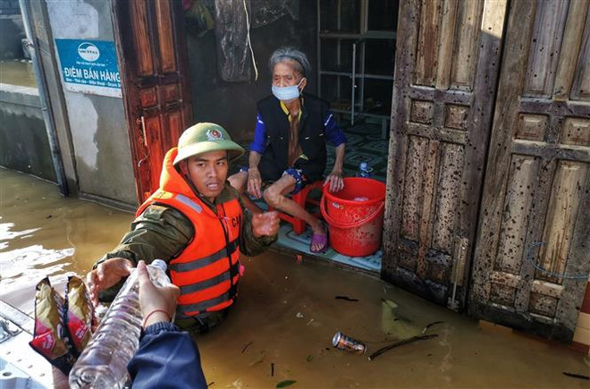 Lực lượng công an huyện Lệ Thủy lội nước, đưa hàng cứu trợ đến những gia đình bị cô lập trong nước lũ. (Ảnh: Thành Đạt/TTXVN) Nghĩa tình đồng bào, chia sẻ yêu thương đùm bọc trong mùa mưa lũ ảnh 1