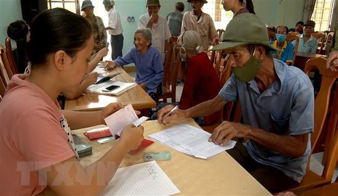 Người dân nhận tiền hỗ trợ khó khăn do dịch COVID-19. (Ảnh: Văn Tý/TTXVN) Mở rộng đối tượng được hỗ trợ do ảnh hưởng của dịch COVID-19 ảnh 1