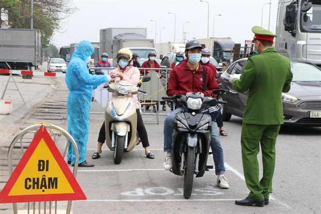 Lực lượng trực chốt kiểm soát cấp tỉnh tại ngã ba Hoàng Long, cửa ngõ phía tây thành phố Hải Dương kiểm tra kỹ giấy tờ của người dân lưu thông qua đây. (Ảnh: Mạnh Minh/TTXVN) Hải Dương: Công sở vắng vẻ, các chốt kiểm dịch kiểm soát chặt chẽ ảnh 2