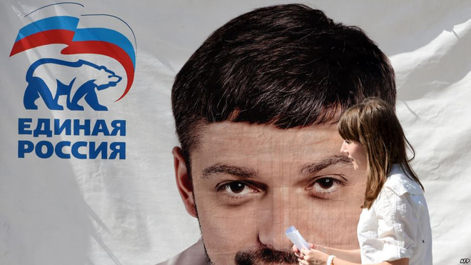 Một người phụ nữ đi qua một tấm poster có hình ông Andrei Kozenko, 1 trong 6 nghị sỹ Nga bị đưa vào danh sách đen của Mỹ. (Nguồn: AFP) Bộ Tài chính Mỹ áp đặt lệnh trừng phạt với 6 nghị sỹ Nga ảnh 1