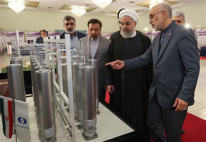 Người đứng đầu Tổ chức Năng lượng nguyên tử Iran (AEOI) Ali Akbar Salehi (phải) báo cáo với Tổng thống Iran Hassan Rouhani (thứ 2, trái) thăm quan một triển lãm nhân Ngày công nghệ hạt nhân ở Tehran. (Nguồn: AFP/TTXVN) Iran tuyên bố tiếp tục giảm cam kết trong thỏa thuận hạt nhân ảnh 1