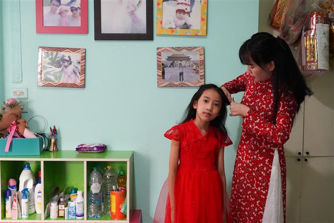 Chị Vinh tết tóc cho con gái. (Ảnh: Đỗ Sinh/TTXVN) Xuân Quý Mão 2023: Đậm đà hồn Tết ở một gia đình Thái-Việt ảnh 4