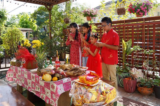 Cả gia đình thành kính cúng tất niên. (Ảnh: Đỗ Sinh/TTXVN) Xuân Quý Mão 2023: Đậm đà hồn Tết ở một gia đình Thái-Việt ảnh 3