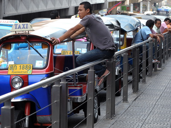 Lái xe tuk-tuk Thái Lan đợi khách hàng tại trung tâm thương mại ở Bangkok. (Nguồn: AFP/TTXVN) Du lịch Thái thiệt hại 300 triệu USD vì tình trạng khẩn cấp ảnh 1
