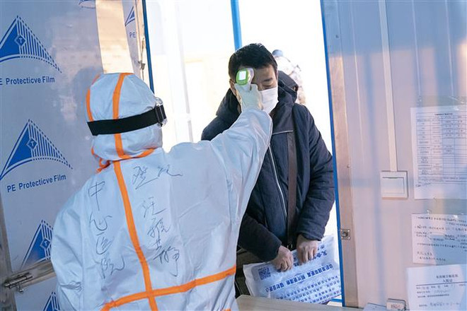 Nhân viên y tế kiểm tra thân nhiệt cho bệnh nhân nhiễm virus COVID-19 tại một bệnh viện dã chiến ở Vũ Hán, Trung Quốc ngày 5/2/2020. (Nguồn: THX/TTXVN) Dịch Covid-19: Trung Quốc ghi nhận số ca phục hồi ngày càng tăng ảnh 1