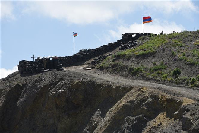 Quốc kỳ Azerbaijan (trái) và quốc kỳ Armenia tại trạm kiểm soát biên giới giữa hai nước ở làng Sotk của Armenia. (Ảnh: AFP/TTXVN) Các nước kêu gọi Armenia và Azerbaijan tìm kiếm giải pháp hòa bình ảnh 1
