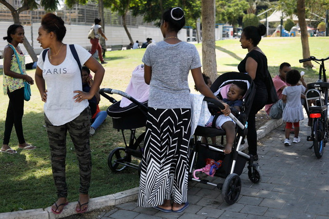 Các gia đình người tị nạn châu Phi nghỉ ngơi gần một công viên ở Tel Aviv. (Nguồn: AFP/TTXVN) Israel hủy kế hoạch trục xuất bắt buộc người tị nạn châu Phi ảnh 1