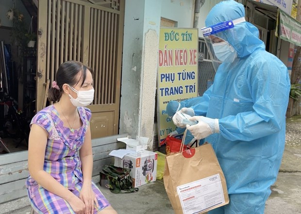 Nhân viên y tế trạm y tế lưu động phường 25, quận Bình Thạnh cấp phát túi thuốc cho F0 điều trị tại nhà. (Ảnh: Đinh Hằng/TTXVN) TP.HCM: Số ca nhập viện trong ngày đã thấp hơn số ca được xuất viện ảnh 2