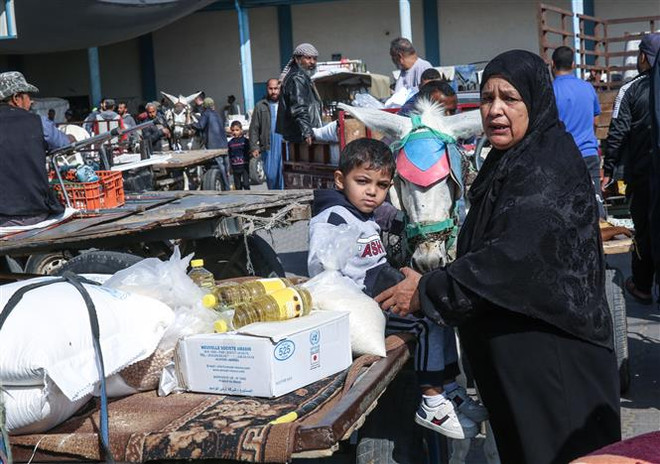 Người dân Palestine nhận hàng cứu trợ tại Dải Gaza. (Ảnh: AFP/TTXVN) LHQ và Qatar hỗ trợ tiền mặt cho người dân Palestine ở Dải Gaza ảnh 1