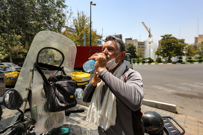 Một người đàn ông uống nước giải nhiệt dưới trời nắng gắt tại Tehran, Iran ngày 11/7/2023. (Ảnh: AFP/TTXVN) ttxvn_nang_nong_3.jpg