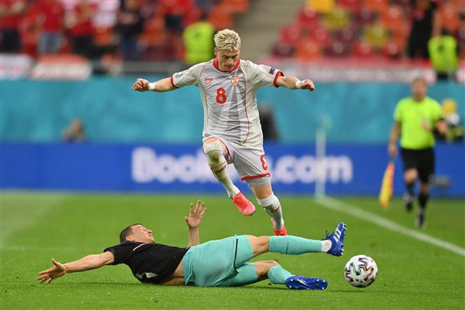 Hậu vệ Bắc Macedonia Ezgjan Alioski (trên) đi bóng trong sự truy cản của hậu vệ Áo Stefan Lainer. (Nguồn: AFP/TTXVN) Cuộc phiêu lưu lãng mạn của đội tuyển Bắc Macedonia sẽ kết thúc? ảnh 1
