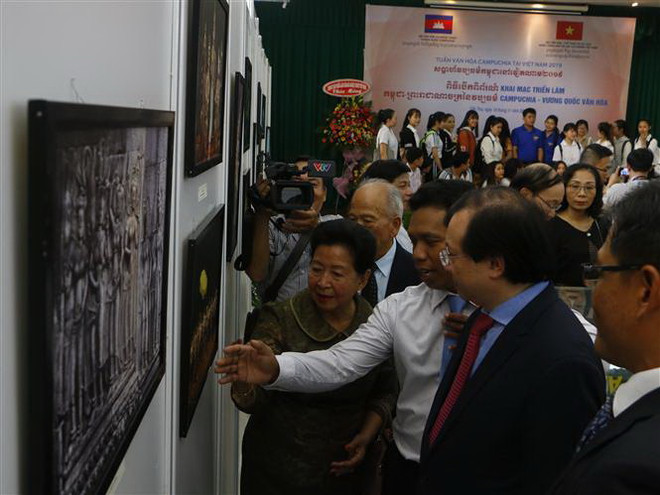 Thứ trưởng Bộ Văn hóa Thể thao và Du lịch Tạ Quang Đông xem ảnh do bà Menh Kossony, Quốc vụ khánh Bộ Văn hóa Nghệ thuật Campuchia giới thiệu. (Ảnh: Thanh Liêm/TTXVN) Khai mạc Triển lãm 'Campuchia - Vương quốc văn hóa' tại Việt Nam ảnh 2