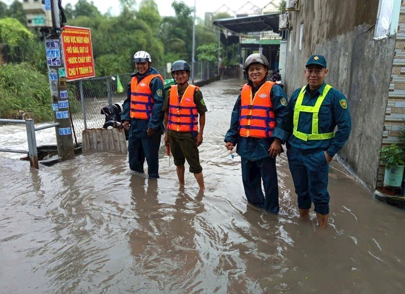 Lực lượng chức năng phường Tân Phước Khánh, thành phố Tân Uyên, tỉnh Bình Dương, có mặt để hỗ trợ người dân, phân luồng giao thông và cảnh báo những đoạn đường ngập sâu, nước chảy siết do mưa lớn. (Ảnh: TTXVN)