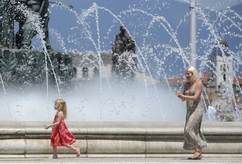 Người dân tránh nóng bên vòi phun nước tại Skopje, Bắc Macedonia. (Ảnh: AFP/TTXVN)