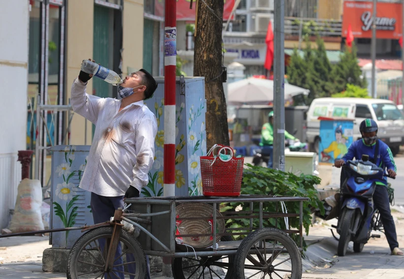 Một người dân bổ sung thêm nước khi phải di chuyển dưới cái nắng, nóng trên 40 độ C. (Ảnh: Hoàng Hiếu/TTXVN)