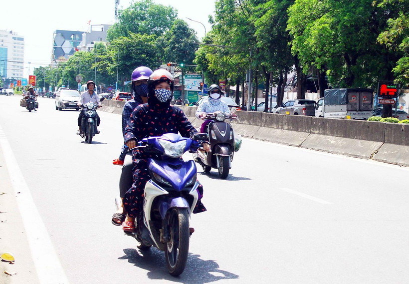 Người dân đều trang bị khẩu trang và mặc áo chống nắng kín khi di chuyển trên đường trong thời tiết nắng nóng. (Ảnh: Tá Chuyên/TTXVN)