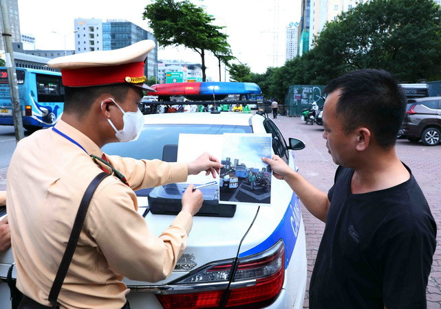 Lực lượng CSGT cho tài xế xe khách xem lại hình ảnh vi phạm để làm căn cứ xử phạt theo quy định pháp luật. (Ảnh: Phạm Kiên/TTXVN)