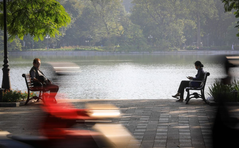 Người dân Thủ đô thư thái ngồi cảm nhận ánh nắng ban mai và tiết thu se lạnh ở hồ Hoàn Kiếm. (Ảnh: Thành Đạt/TTXVN)