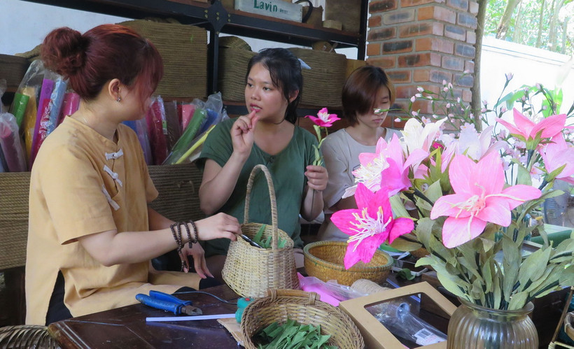 Thanh Nhàn (áo xanh) đang giao tiếp với các bạn khuyết tật bằng ngôn ngữ ký hiệu. (Ảnh: Tường Vi/TTXVN)