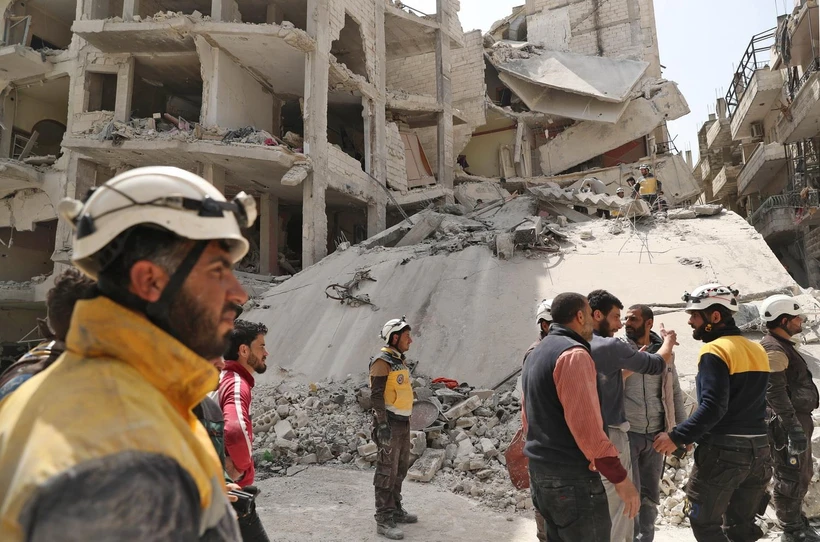 Nhân viên phòng vệ dân sự Syria tìm kiếm các nạn nhân tại khu vực nhà bị sập sau vụ nổ ở Jisr al-Shughur, tỉnh Idlib ngày 24/4. (Ảnh: AFP/TTXVN)