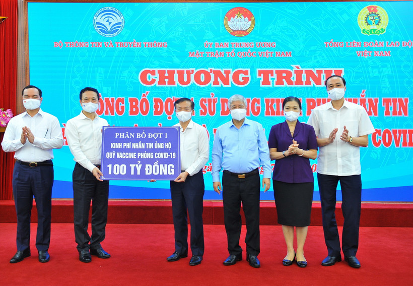 Bộ trưởng Bộ Thông tin và Truyền thông Nguyễn Mạnh Hùng (trái) trao số tiền nhắn tin 100 tỷ đồng ủng hộ Quỹ vaccine phòng COVID-19 (phân bổ đợt 1) cho Giám đốc Ban quản lý Quỹ vaccine phòng COVID-19 Nguyễn Quang Vinh. (Ảnh: Minh Đức/TTXVN)