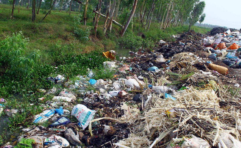 Lượng rác quá tải, chất thành từng đống tràn xuống cả kênh mương nước thủy lợi gây tắc nguồn nước và tràn ra đồng ruộng xung quanh. (Ảnh: Tá Chuyên/TTXVN)