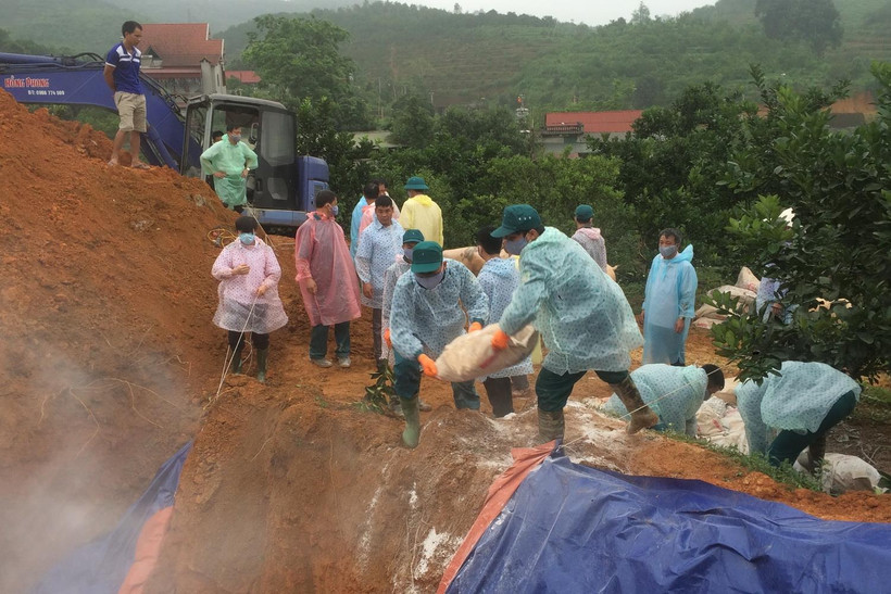 Các lực lượng chức năng dùng vôi tiêu hủy lợn nhiễm bệnh. (Ảnh: Ngọc Anh/TTXVN)