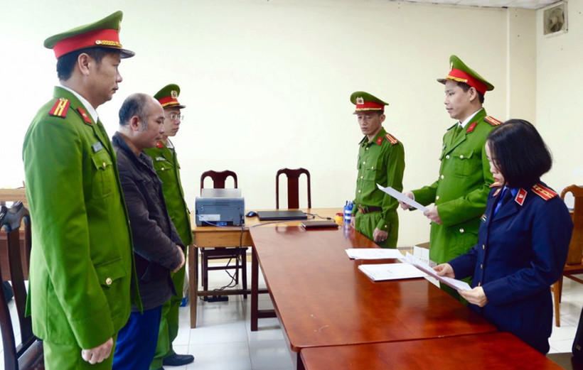 Lực lượng chức năng đọc lệnh khởi tố và bắt tạm giam Trần Quang Anh. (Ảnh: TTXVN phát)