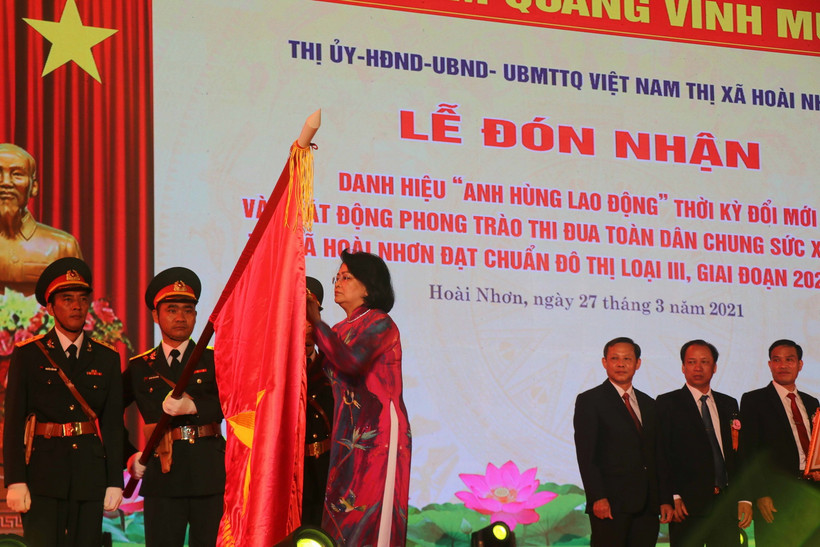 Phó Chủ tịch nước Đặng Thị Ngọc Thịnh gắn huy hiệu Anh hùng Lao động thời kỳ đổi mới lên cờ truyền thống của thị xã Hoài Nhơn, tỉnh Bình Định. (Ảnh: Phạm Kha/TTXVN)