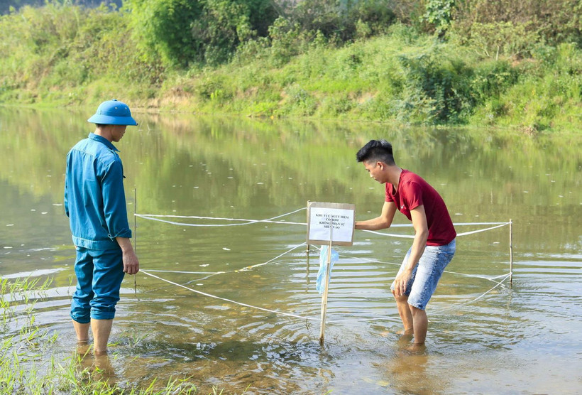 Lực lượng dân quân quây chắn và đặt biển cảnh báo tại khu vực phát hiện quả bom. (Ảnh: Xuân Tư/TTXVN)