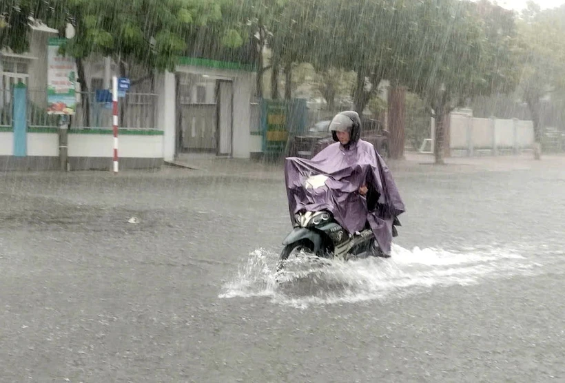 Tuyến đường ở thành phố Tam Kỳ bị ngập nước khiến người và phương tiện lưu thông rất khó khăn. (Ảnh: Trịnh Bang Nhiệm/TTXVN)