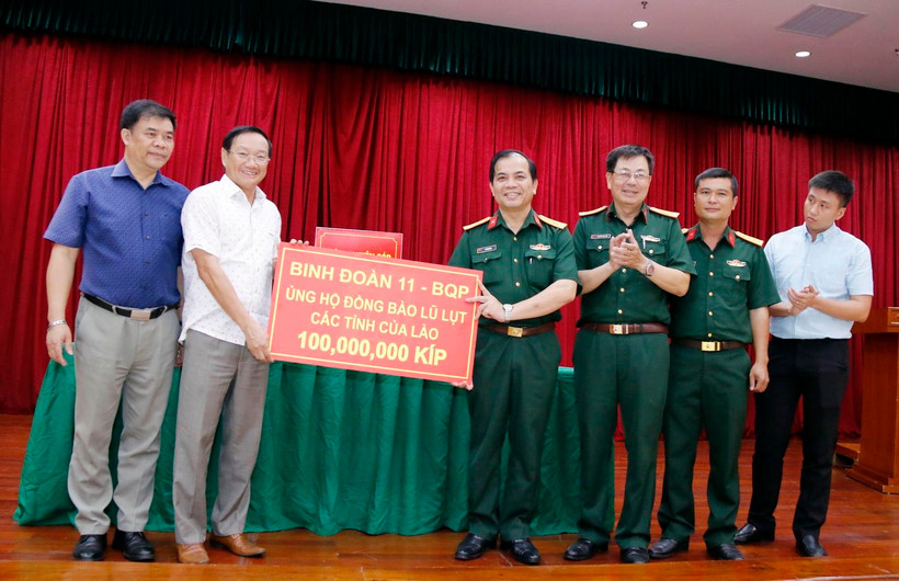 Đại diện Binh đoàn 11 thuộc Bộ Quốc phòng Việt Nam, trao số tiền ủng hộ 100 triệu kíp (hơn 11.000 USD). (Ảnh: Phạm Kiên/TTXVN)