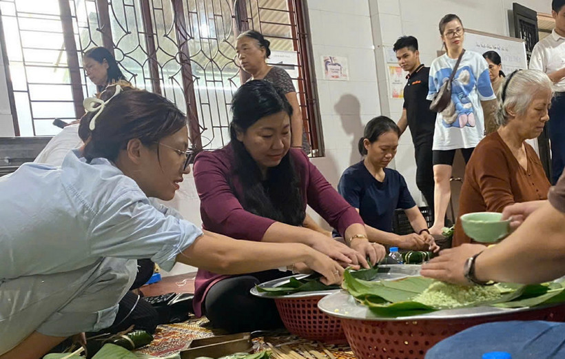 Chủ tịch Ủy ban MTTQ Việt Nam thành phố Hà Nội Nguyễn Lan Hương gói bánh chưng với người dân để chuyển đến những nơi bị lũ lụt. (Ảnh: TTXVN phát)