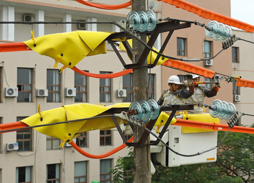 Công nhân Đội sửa chữa Hotline thay sứ trên đường dây 22kV đang mang điện tại khu vực quận Long Biên, Hà Nội. (Ảnh: Ngọc Hà/TTXVN)