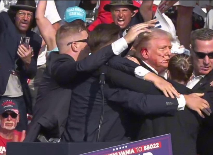 Cựu Tổng thống Donald Trump được mật vụ Mỹ hộ tống rời khỏi bục diễn thuyết trong cuộc vận động tranh cử ở thành phố Butler, bang Pennsylvania sau khi xảy ra vụ nổ súng. (Ảnh: THX/TTXVN)