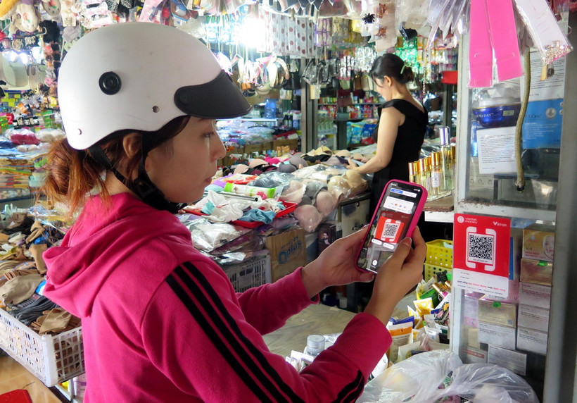 Người dân quét mã QR thanh toán không dùng tiền mặt tại chợ Phù Cát, thị trấn Ngô Mây, tỉnh Bình Định. (Ảnh: Lê Ngọc Phước/TTXVN)