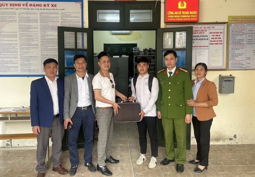 Em Nguyễn Bá Biền (thứ 3 từ phải) trả lại tiền cho người đánh rơi. (Ảnh: TTXVN phát)