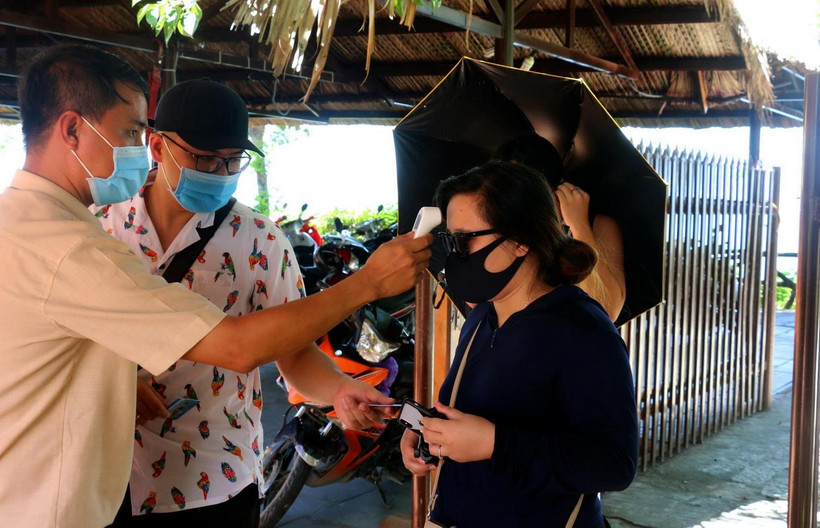 Đo thân nhiệt cho du khách đến tham quan danh thắng Hòn Chồng, thành phố Nha Trang. (Ảnh: Phan Sáu/TTXVN)