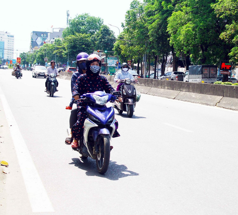 Người dân đều trang bị khẩu trang và mặc áo chống nắng kín khi di chuyển trên đường trong thời tiết nắng nóng. (Ảnh: Tá Chuyên/TTXVN)