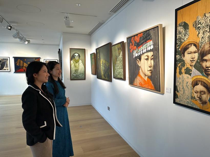 Nhân viên phòng tranh Thăng Long Art Gallery giới thiệu về các tác phẩm với khách tham quan. (Ảnh: TTXVN phát)