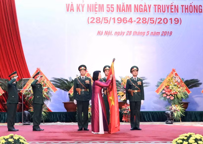 Phó Chủ tịch nước Đặng Thị Ngọc Thịnh gắn Danh hiệu Anh hùng Lực lượng Vũ trang Nhân dân lên lá cờ truyền thống của Cục Đối ngoại. (Ảnh: Văn Điệp/TTXVN)